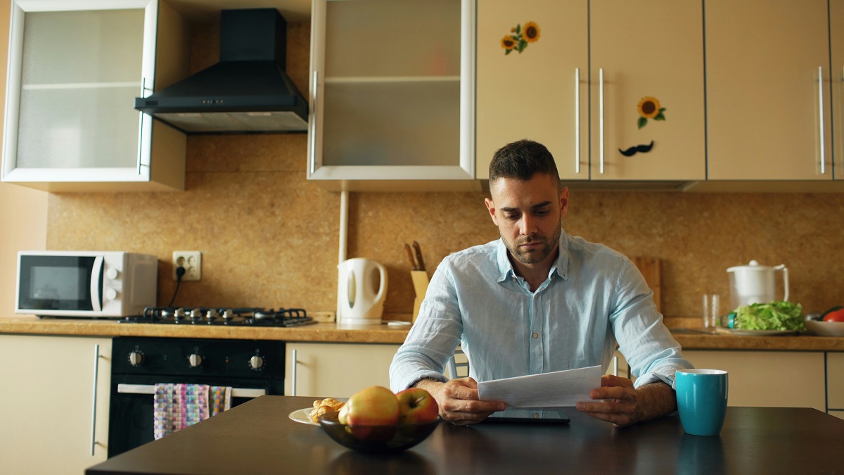man looking at bills in the kitchen